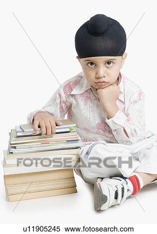 Stock Photography - Portrait of a boy sitting with books . Fotosearch
