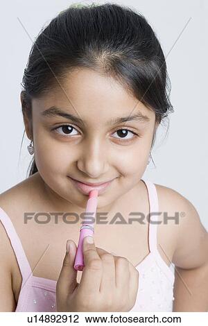 Stock Image - Portrait of a girl applying lipstick. Fotosearch
