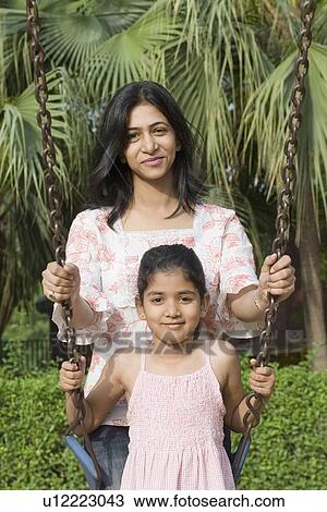 Portrait of a girl on a swing with her mother standing beside her View Large Photo Image Stock Image - Portrait of a girl on a swing with her mother standing beside her. Fotosearch