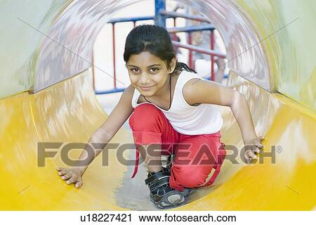 Portrait of a girl playing in a slide View Large Photo Image Stock Image - Portrait of a girl playing in a slide. Fotosearch