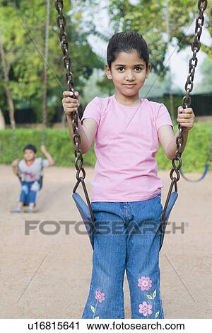 Stock Image - Portrait of a girl sitting on a swing. Fotosearch