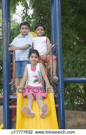 Portrait of a girl sliding on a slide with two boys standing beside her View Large Photo Image Stock Image - Portrait of a girl sliding on a slide with two boys standing beside her. Fotosearch