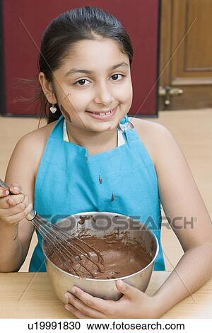 Stock Image - Portrait of a girl stirring chocolate sauce with an egg beater. Fotosearch
