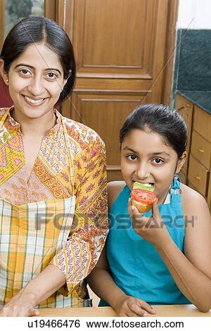 Portrait of a mid adult woman smiling beside her daughter eating a sandwich View Large Photo Image Stock Photograph - Portrait of a mid adult woman smiling beside her daughter eating a sandwich. Fotosearch