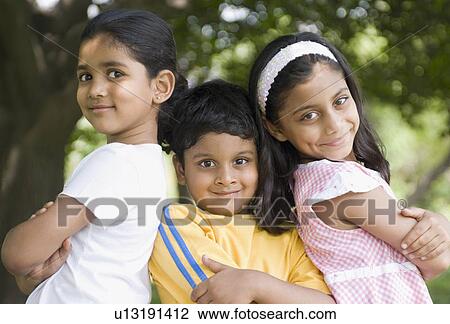 Stock Image - Portrait of two girls and a boy standing with their arm crossed. Fotosearch