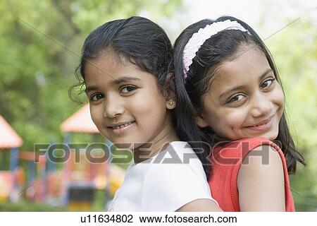 Portrait of two girls back to back and smiling View Large Photo Image Stock Image - Portrait of two girls back to back and smiling. Fotosearch