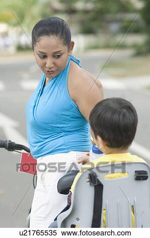 Stock Photography - Side profile of a mid adult woman looking at her son riding a bicycle. Fotosearch