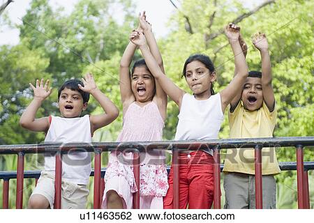 Two boys and two girls standing with their arms raised View Large Photo Image Stock Image - Two boys and two girls standing with their arms raised. Fotosearch