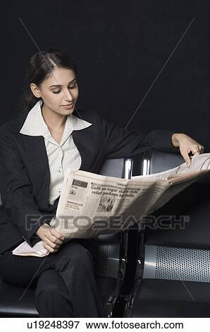 Stock Photo - Businesswoman sitting on a bench and reading a newspaper. Fotosearch