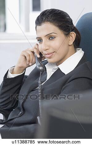 Stock Photography - Businesswoman talking on the telephone in an office. Fotosearch