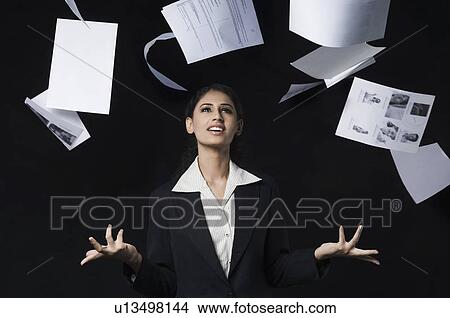 Picture - Businesswoman throwing papers in air and smiling. Fotosearch