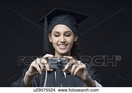 Close-up of a young female graduate holding a digital camera View Large Photo Image Picture - Close-up of a young female graduate holding a digital camera. Fotosearch