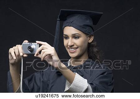 Close-up of a young female graduate holding a digital camera View Large Photo Image Stock Photography - Close-up of a young female graduate holding a digital camera. Fotosearch
