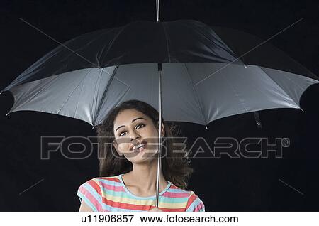 Close-up of a young woman under an umbrella and smiling View Large Photo Image Stock Photo - Close-up of a young woman under an umbrella and smiling. Fotosearch