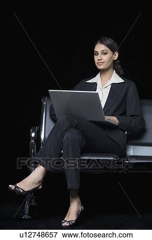 Portrait of a businesswoman sitting on a bench and using a laptop View Large Photo Image Stock Photo - Portrait of a businesswoman sitting on a bench and using a laptop. Fotosearch