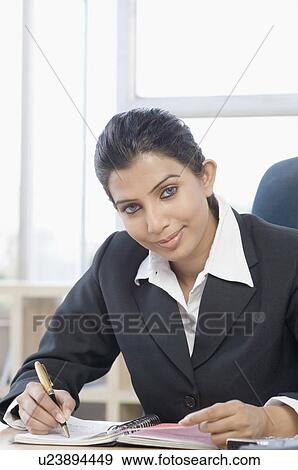 Portrait of a businesswoman writing on a ring binder View Large Photo Image Stock Photo - Portrait of a businesswoman writing on a ring binder. Fotosearch