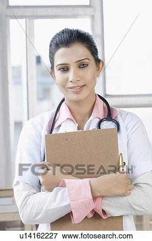 Stock Photo - Portrait of a female doctor standing with a stethoscope around her neck. Fotosearch