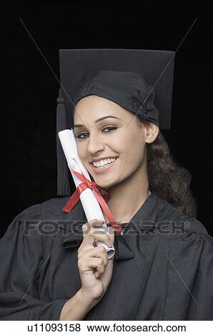 Stock Photo - Portrait of a young female graduate holding a diploma and smiling. Fotosearch
