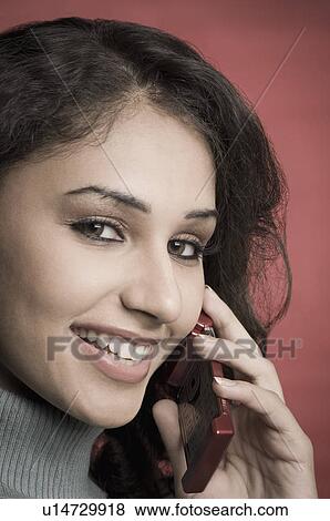 Stock Photo - Portrait of a young woman talking on a mobile phone and smiling. Fotosearch