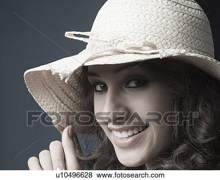 Stock Photo - Portrait of a young woman wearing a straw hat and smiling. Fotosearch
