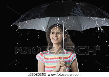Young woman holding an umbrella and smiling View Large Photo Image Stock Image - Young woman holding an umbrella and smiling. Fotosearch