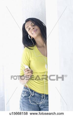 Stock Photo - Close-up of a young woman listening to an mp3 player. Fotosearch