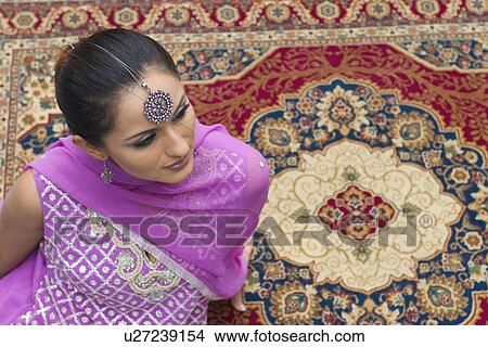 High angle view of a mid adult woman sitting on a carpet in salwar kameez View Large Photo Image Picture - High angle view of a mid adult woman sitting on a carpet in salwar kameez. Fotosearch