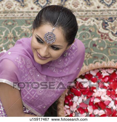 High angle view of a mid adult woman sitting on a carpet in salwar kameez with a bowl of petals View Large Photo Image Stock Photo - High angle view of a mid adult woman sitting on a carpet in salwar kameez with a bowl of petals. Fotosearch