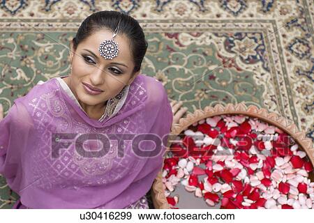High angle view of a mid adult woman sitting on a carpet in salwar kameez with a bowl of petals View Large Photo Image Stock Photo - High angle view of a mid adult woman sitting on a carpet in salwar kameez with a bowl of petals. Fotosearch
