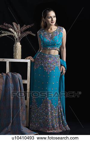 Stock Image - Mid adult woman standing in lehenga choli. Fotosearch