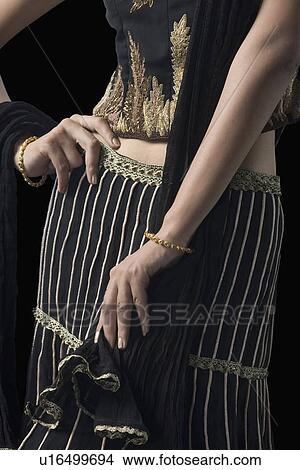 Mid section view of a young woman standing in lehenga choli View Large Photo Image Picture - Mid section view of a young woman standing in lehenga choli. Fotosearch