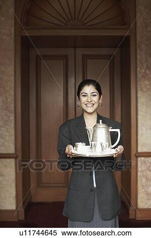 Stock Photography - Portrait of a waitress holding a serving tray. Fotosearch