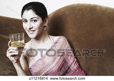 Picture - Portrait of a young woman holding a glass of whiskey. Fotosearch
