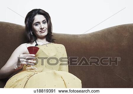 Stock Image - Portrait of a young woman holding a martini glass. Fotosearch