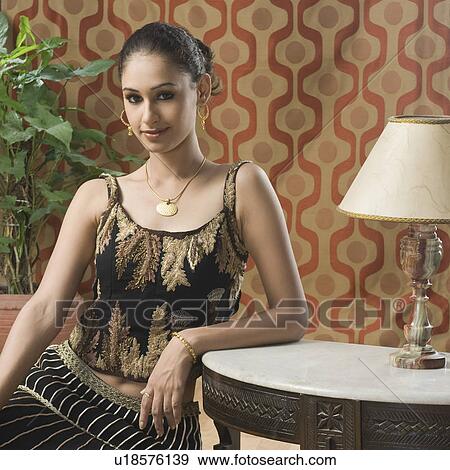 Stock Photo - Portrait of a young woman in lehenga choli and sitting on the floor. Fotosearch