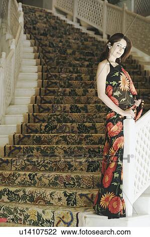 Stock Image - Portrait of a young woman standing on a staircase. Fotosearch
