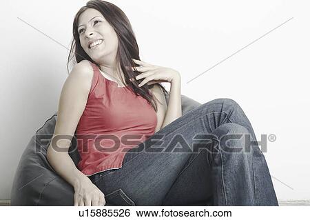 Young woman sitting on a bean bag View Large Photo Image Stock Photograph - Young woman sitting on a bean bag. Fotosearch