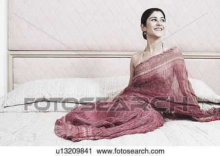 Young woman sitting on the bed View Large Photo Image Stock Image - Young woman sitting on the bed. Fotosearch