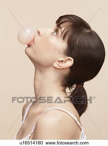 Stock Image - Mid adult woman blowing bubblegum. Fotosearch
