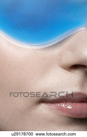 Stock Image - Young woman wearing eye mask, close-up. Fotosearch