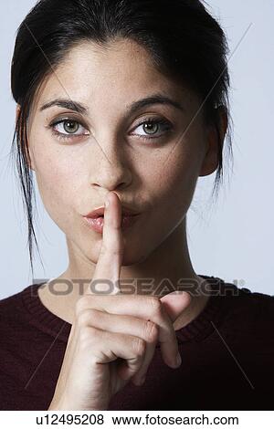 Stock Photo - Young woman with finger over mouth. Fotosearch
