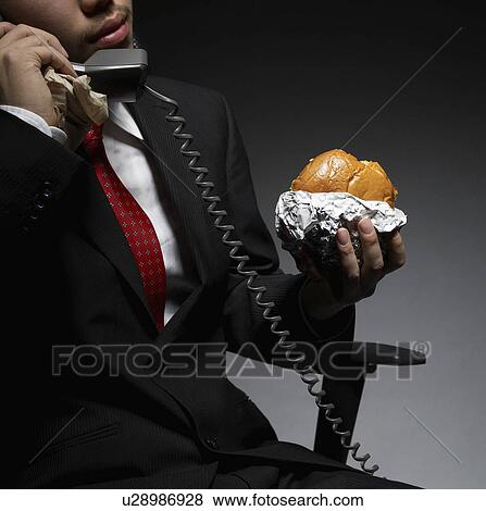 Stock Photo - Businessman Having Lunch While on Phone. Fotosearch