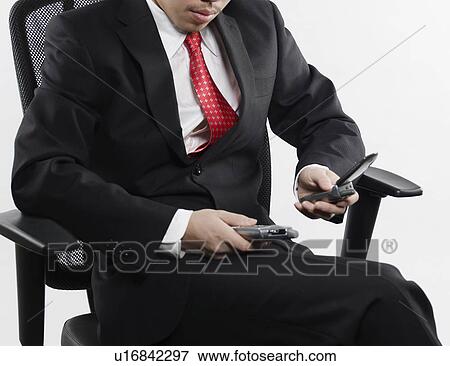 Businessman Using PDA and Mobile Phone View Large Photo Image Stock Photo - Businessman Using PDA and Mobile Phone. Fotosearch