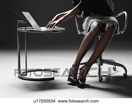 Picture - Businesswoman using laptop (low section). Fotosearch