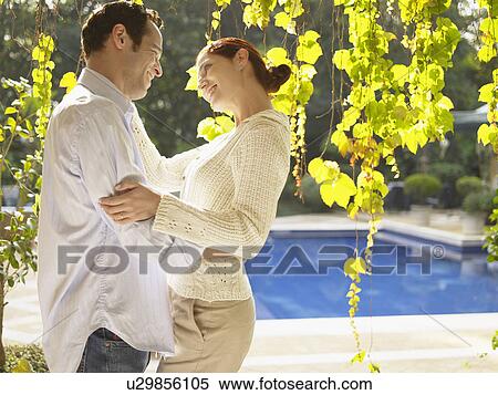 Stock Photography - Couple hugging near swimming pool. Fotosearch