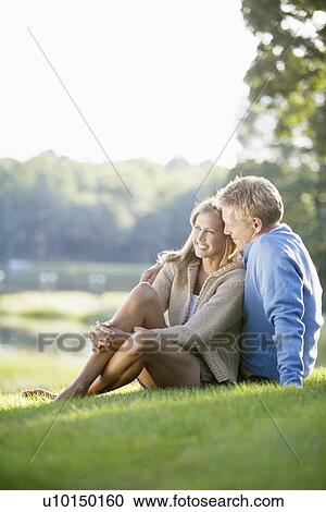 Stock Image - Couple sitting on lawn. Fotosearch