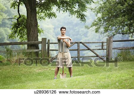 Gardener leaning against spade in field (portrait) View Large Photo Image Stock Photograph - Gardener leaning against spade in field (portrait). Fotosearch