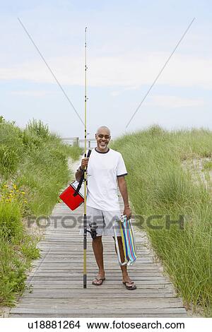 Man with fishing equipment standing on boardwalk View Large Photo Image Picture - Man with fishing equipment standing on boardwalk. Fotosearch