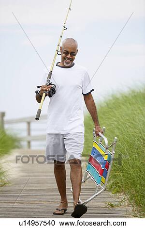 Man with fishing rod and folding chair walking on boardwalk View Large Photo Image Stock Image - Man with fishing rod and folding chair walking on boardwalk. Fotosearch