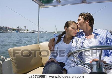 Stock Image - Young adult man kissing on forehead of woman on a cruiser, Front View, Side View. Fotosearch